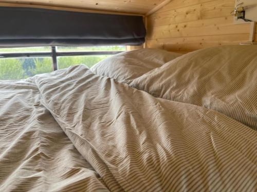 an unmade bed in a room with a window at Op zoek naar een leuke overnachting Te huur Prachtig Tiny House De Hutte in Siddeburen