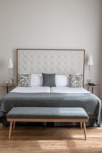 a bedroom with a large bed with a bench next to it at Gran Hotel Havana 4Sup by Escampa Hotels in Barcelona