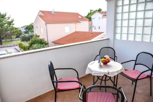 a balcony with chairs and a table with a bowl of fruit at Apartments Purkovic in Vodice