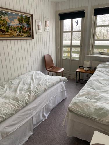 a bedroom with two beds and a chair and two windows at Munkebo B&B, Thy in Thisted