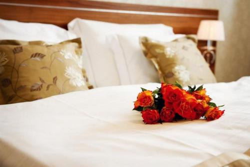 a bouquet of red roses sitting on a white bed at Wellness hotel Spark in Malacky