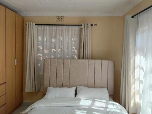 a bed with white pillows in a bedroom with a window at Kelhanil Homes in Narok