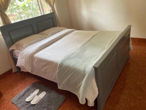a bed with white sheets and a pair of slippers at Suzie's Nest in Lilongwe