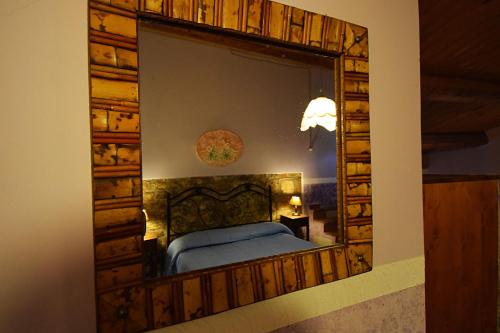 a mirror on a wall with a bed in a room at Giucalem La Casa Negli Orti in Piazza Armerina