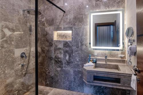 ein Badezimmer mit Dusche, Waschbecken und Spiegel in der Unterkunft Grand hotel alhamra in Dschidda