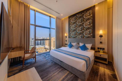 ein Hotelzimmer mit Bett, Schreibtisch und großem Fenster in der Unterkunft Grand hotel alhamra in Dschidda