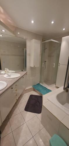 a bathroom with two sinks and a shower and a tub at Colocation Du Grand Large in Décines-Charpieu