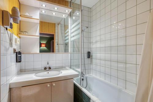 a bathroom with a sink and a tub and a mirror at Brit Hotel Florimont in Saint-Ferréol
