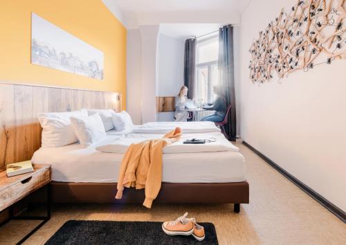 a hotel room with two beds and a woman sitting at a desk at Three Little Pigs Hostel - Your Berlin Castle in Berlin
