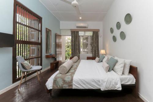 a bedroom with a bed and a chair and windows at Villa Monsoon in Mount Lavinia