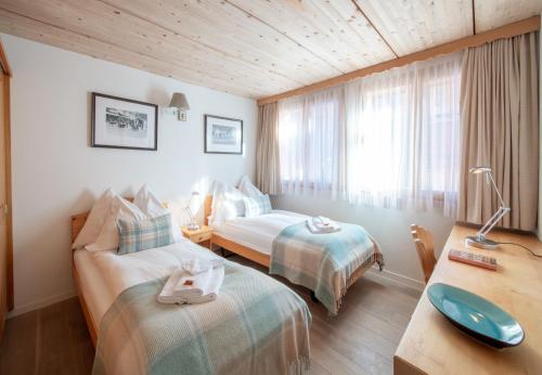 a hotel room with two beds and a desk at Chalet Stella Penthouse Residence in Wengen