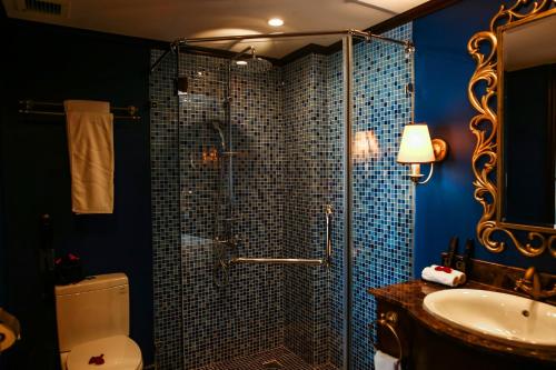 a bathroom with a shower with a toilet and a sink at The Scarlett Boutique Hotel in Hue