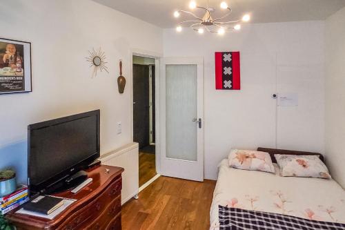 a living room with a flat screen tv and a table with a couch at B&B West City Amsterdam in Amsterdam
