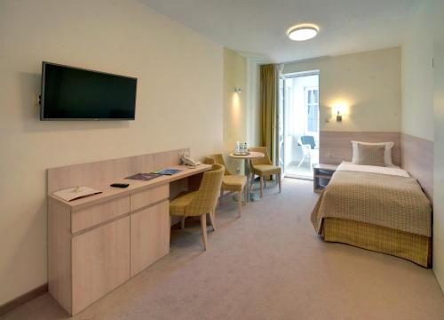 a hotel room with a bed and a desk with a television at Hotel Willa Odkrywców in Szklarska Poręba