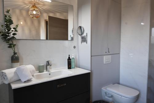 a bathroom with a sink and a toilet and a mirror at I Salini - T3 élégant & calme près du centre - Classé 4 étoiles in Porto-Vecchio