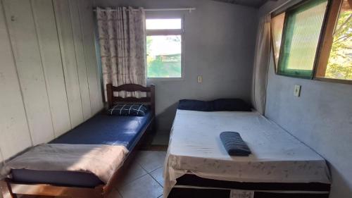 two beds in a small room with a window at Alaercio goulart in Palhoça