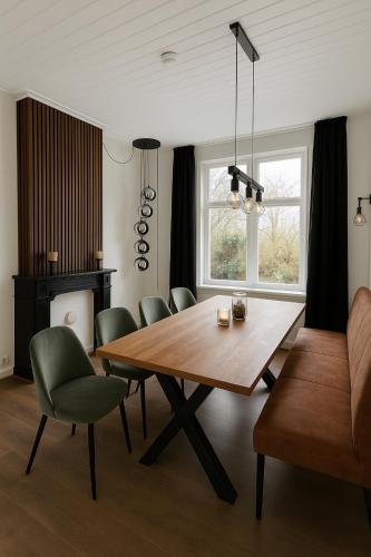a dining room with a wooden table and chairs at Groepsverblijf Villa d'Uylenburgh in Hommerts