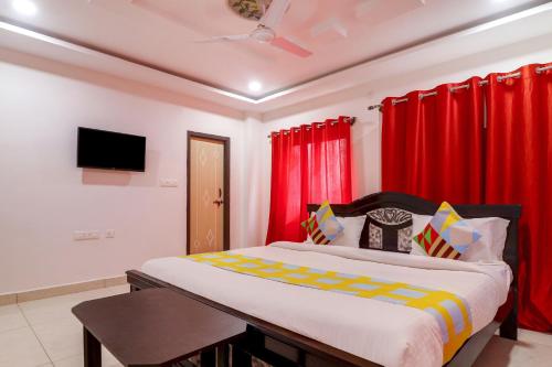 a bedroom with a large bed with red curtains at Hotel O Home RBS Homes in Hyderabad