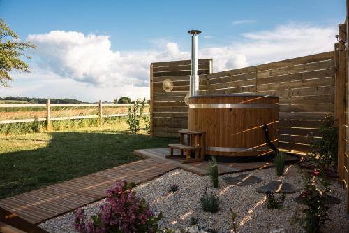 a wooden plunge tub with a bench next to a fence at Bulle à la Belle étoile in Clécy