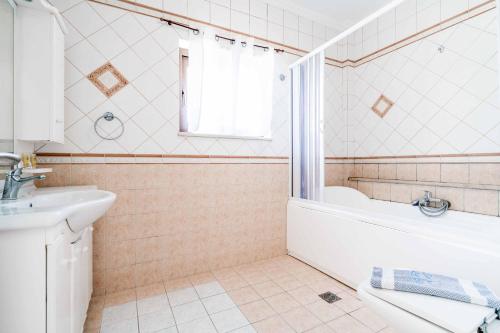 a bathroom with a white tub and a sink at Villa Zante Odysseus in Planos
