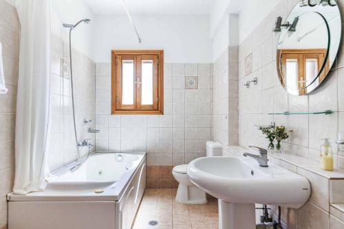 a white bathroom with a tub and a sink and a toilet at Villa Terracotta in Alikias