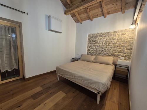 a bedroom with a bed and a brick wall at Dimora del Serva in Belluno