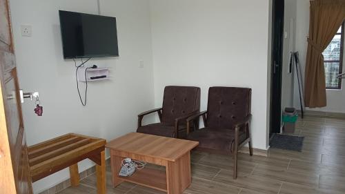 two chairs and a table and a tv on a wall at Makok Seaview roomstay in Kampung Penarik