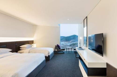 a hotel room with two beds and a flat screen tv at Hotel Ora Incheon in Incheon