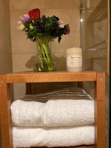 a vase of flowers sitting on a shelf with towels at Andromeda Sunset Suite & Spa in Tel Aviv