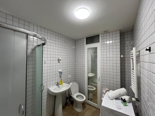 a white bathroom with a toilet and a sink at Central Cozy 2-Bedroom in Tbilisi City