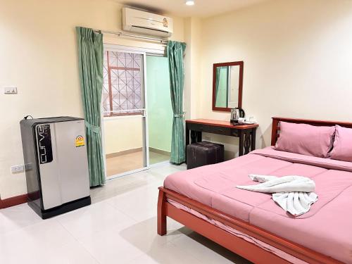 a bedroom with a pink bed and a refrigerator at Khan House Patong in Patong Beach