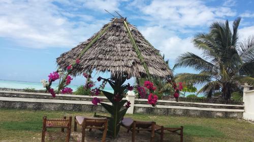 a group of chairs and a straw hut with flowers at White Sands in Paje