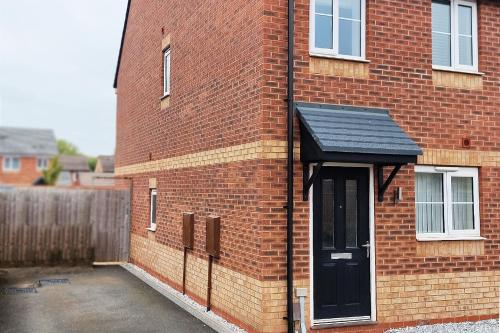 a brick building with a black door on it at Modern 3-Bedroom - VAT Included - Private Drive Parking in Stafford