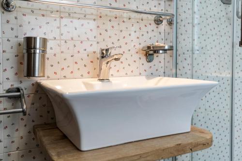 a white sink in a bathroom with wallpaper at Hotel Jumeaux in Breuil-Cervinia