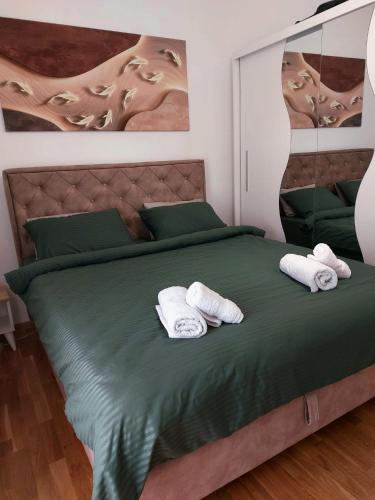 a bedroom with a green bed with towels on it at Apartman Smaragd in Loznica