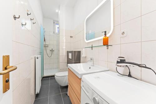 a bathroom with a sink and a toilet and a mirror at primeflats - Apartments Genter Berlin-Wedding in Berlin