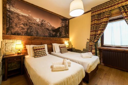 two beds in a room with a painting on the wall at Hotel Jumeaux in Breuil-Cervinia