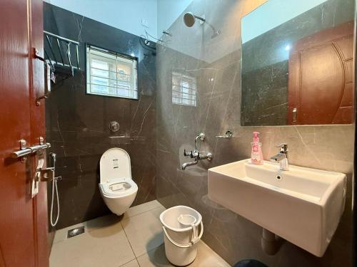 a bathroom with a white toilet and a sink at Malpe Serene Stays in Malpe