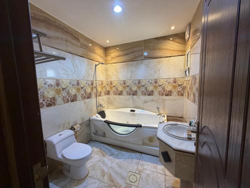 a bathroom with a tub and a toilet and a sink at اكارم - إشبيلية - Akarem - iishbilia - اقتصادي in Riyadh