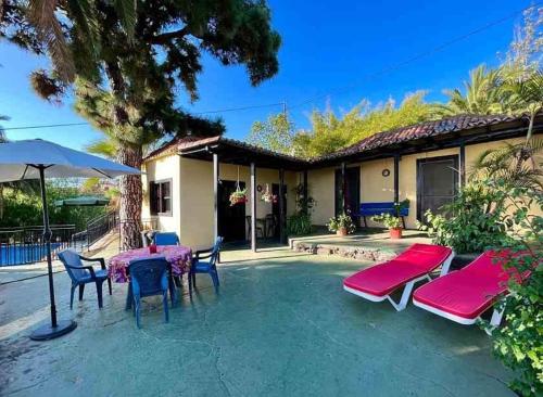 eine Terrasse mit Tisch, Stühlen und Sonnenschirm in der Unterkunft Finca Panadera, Ferienhaus in Tijarafe in Tijarafe