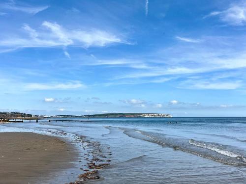 a beach with a blue sky and the ocean at Luccombe Villa Holiday Apartments in Shanklin
