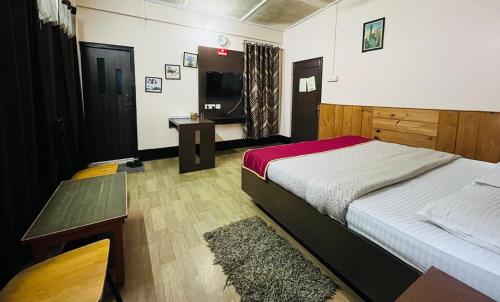 a bedroom with a bed and a table and a television at Executive Guest House in Guwahati