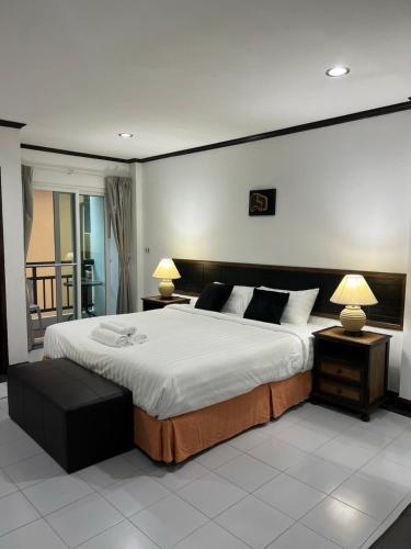 a bedroom with a large bed with two lamps and a balcony at Pathaya in Ban Kata