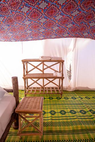 a table and a stool in a room with a wall at Eden Lodge - Desert Camp in Kébémèr