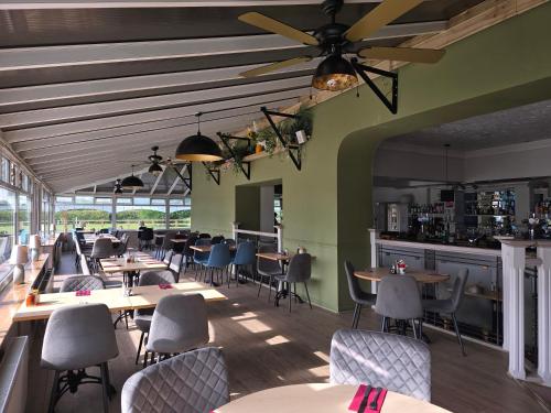 a restaurant with tables and chairs and a bar at Ashburnham Hotel in Pembrey