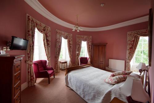 a bedroom with pink walls and a bed and a tv at Overwater Hall in Bassenthwaite