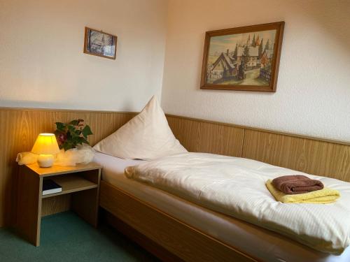 a bed in a room with a lamp on a table at Hotel-Pension Flechsig in Hartmannsdorf