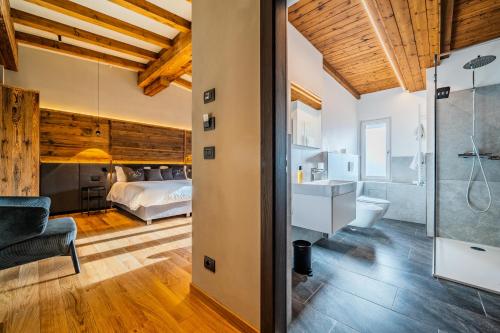 a bedroom with a bed and a bathroom with a shower at Hotel Bel Sit Spa in Valle di Cadore