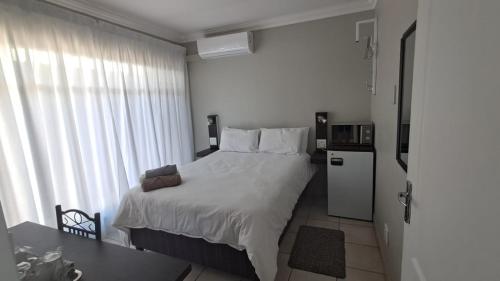 a bedroom with a large white bed and a refrigerator at Chrisserus Guest Rooms in Bloemfontein