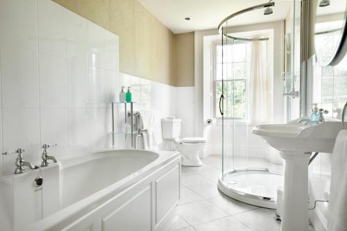 a bathroom with a tub and a sink and a toilet at Overwater Hall in Bassenthwaite